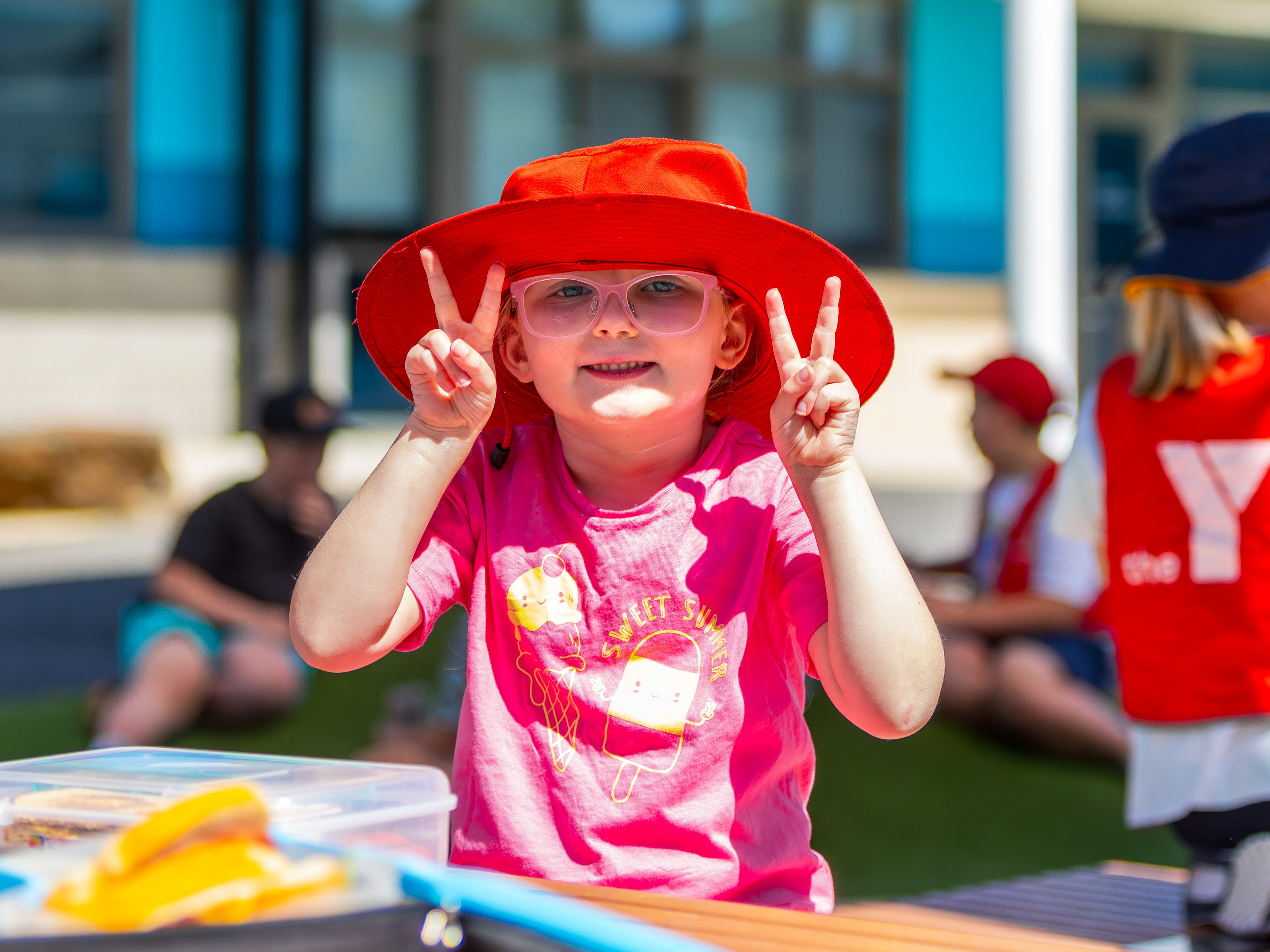 Girl in a red hat doing the peace sign with both hands